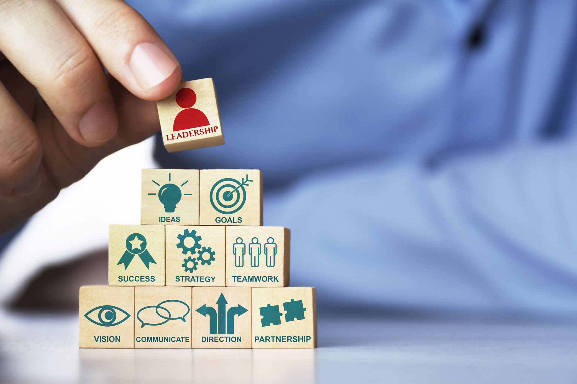 Leadership concept. Hand arranging pyramid shape wood blocks with business strategy and leadership icons